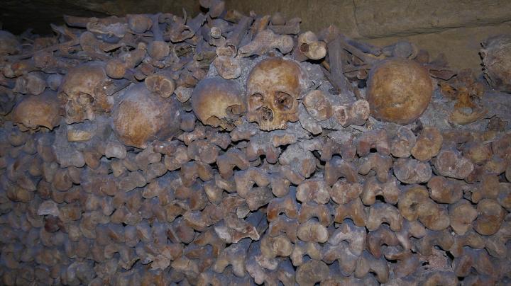 Paris - Catacombes - Une hague d'ossements : un mur de fémurs et de crânes et derrière les autres ossements en vrac